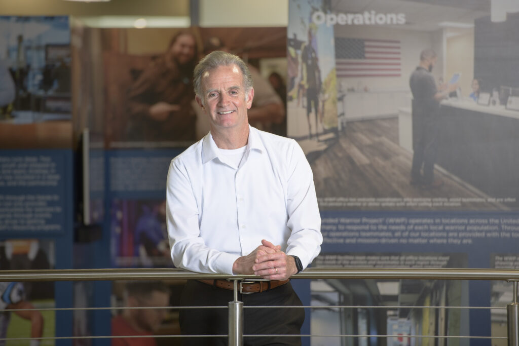 Walt Piatt standing in Wounded Warrior Project headquarters in front of historical military posters.